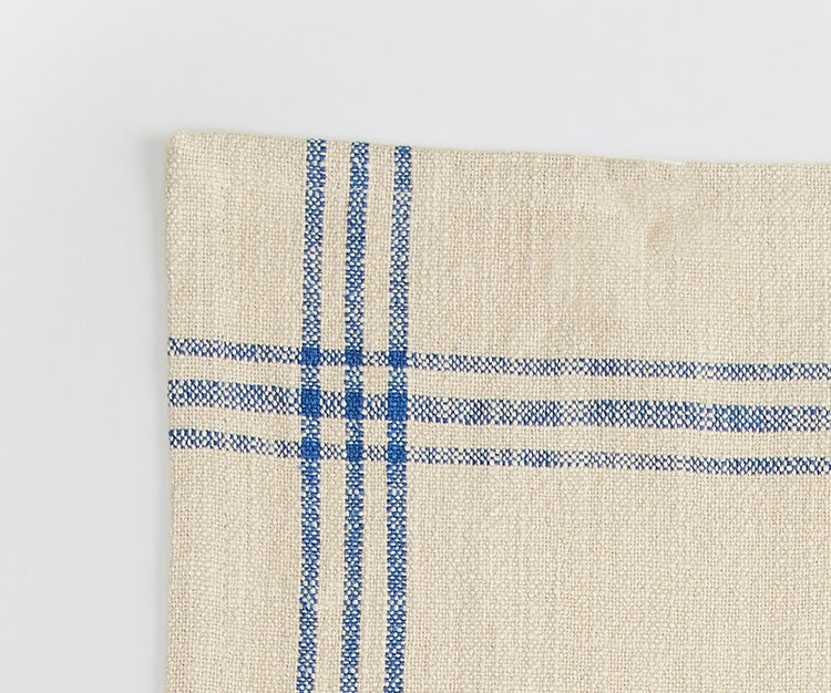 A close-up shot of the corner of a Misen Kitchen Towel, with the stitching and blue stripe pattern clearly visible.