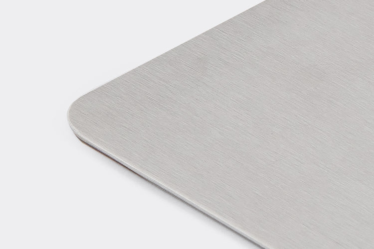 A side-angle view of part of the Misen Bench Scraper’s metal blade, showing its rounded corners, on a white background.