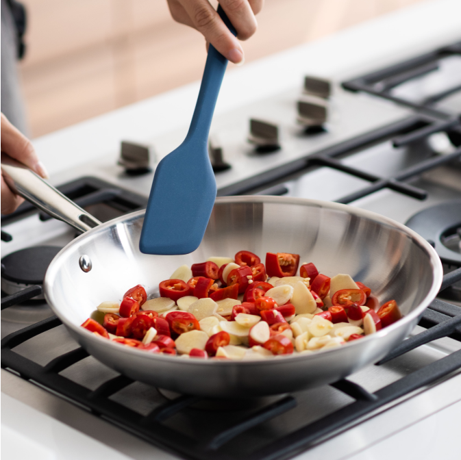 Sauteéing chili peppers and water chestnuts in a Misen Stainless Steel Skillet with a blue Misen Mixing Spatula