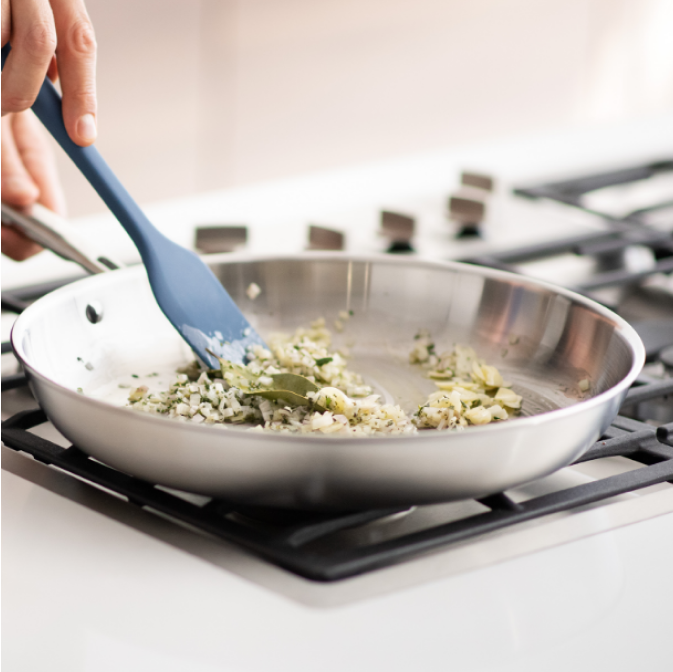 Sauteéing onions and basil in a Misen Stainless Steel Pan with a blue Misen Mixing Spatula