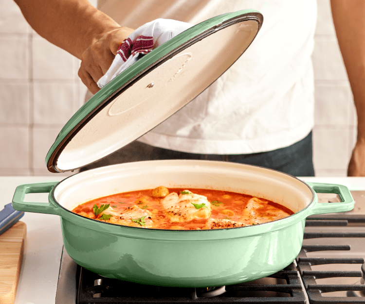 Cooking tomato-poached fish in a sage green Misen Enameled Cast-Iron Braiser.
